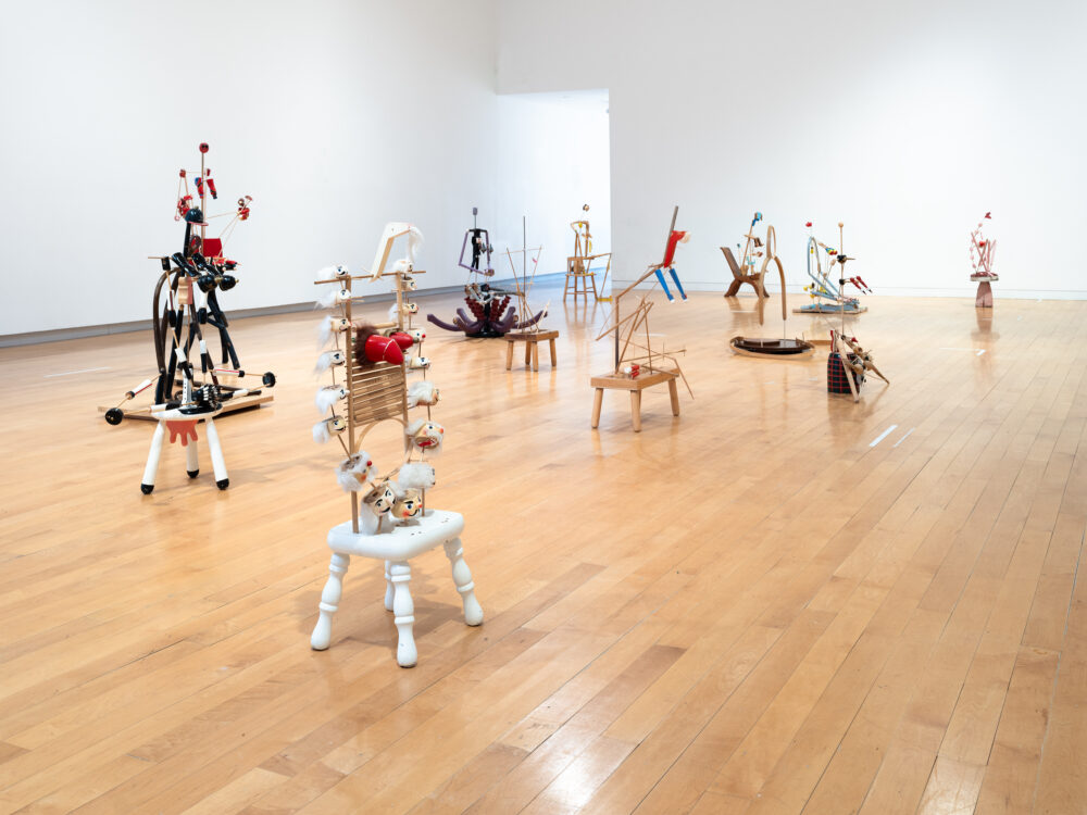 A three quarters view of an installation of figurative sculptures filling a gallery space.