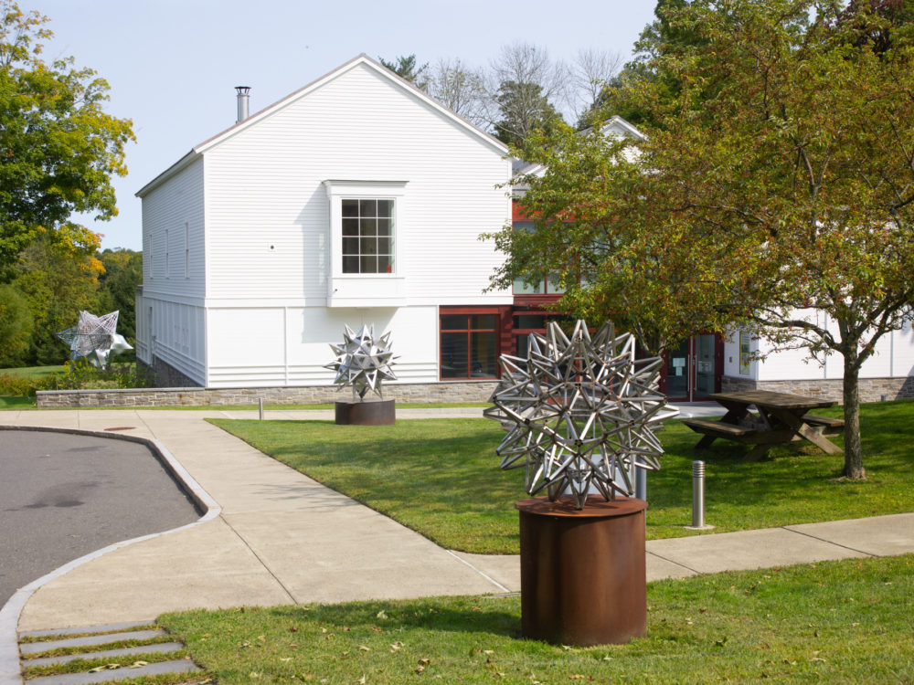 Façade of The Aldrich Contemporary Art Museum with three star sculptures on the grounds.