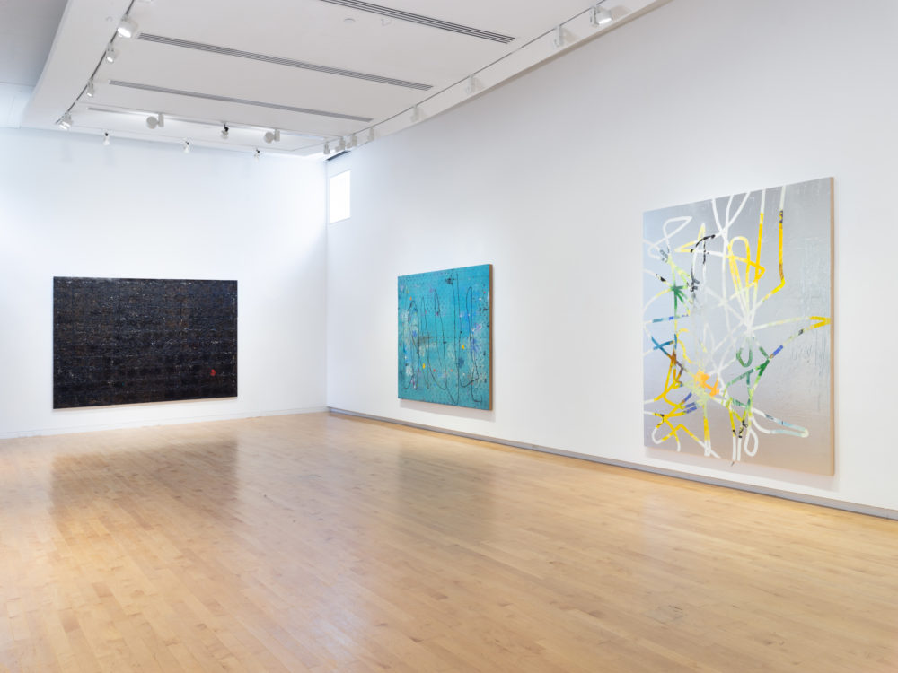 Three canvas works on white gallery walls