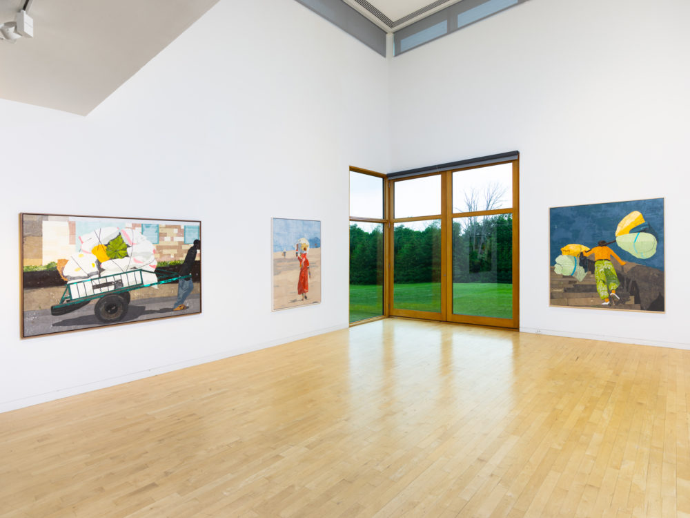 Three large canvas works on white gallery walls with a large window in the background