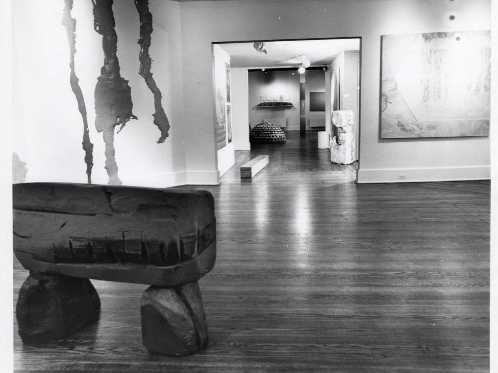 Black and white photo with an abstract sculpture in the foreground and a doorway in the background.