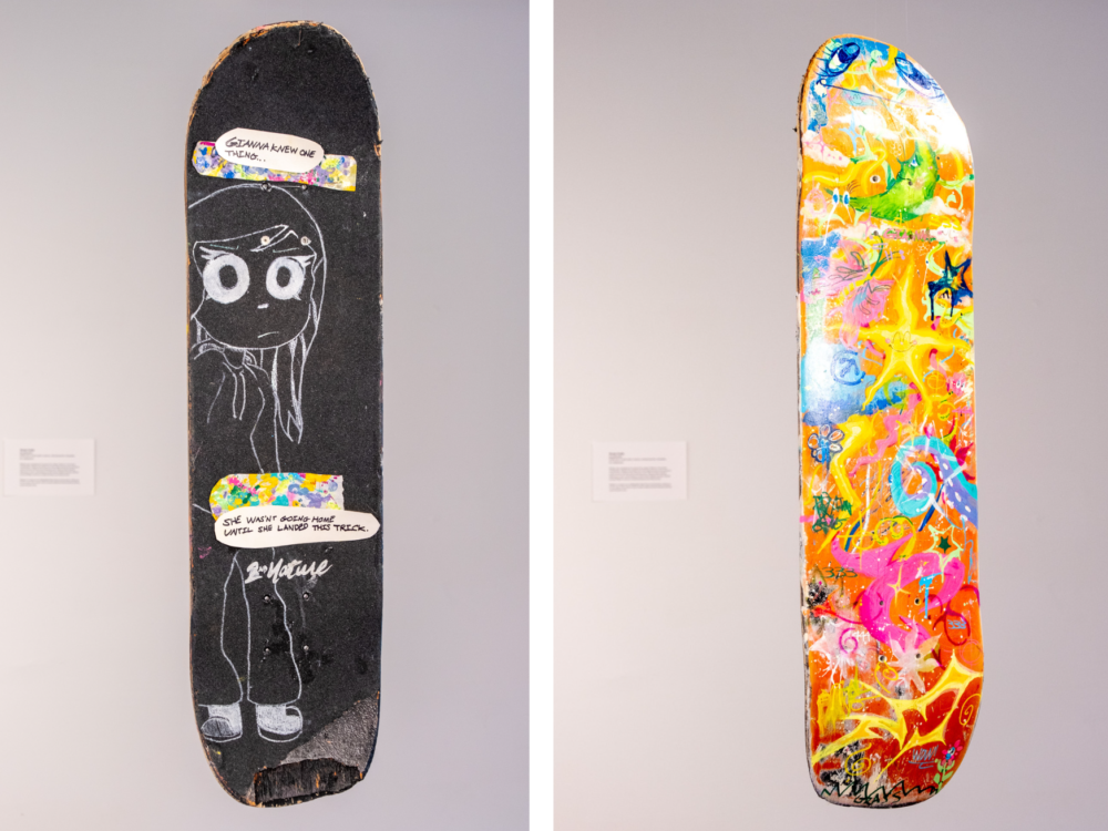 A painted skateboard with a chalk portrait on the front and brightly colored doodles on the back.