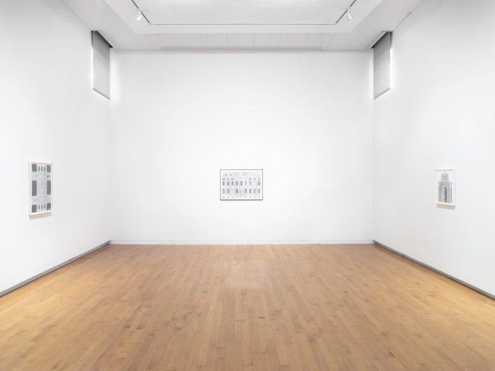 Image of the end of a gallery with three framed drawings hung on the walls.