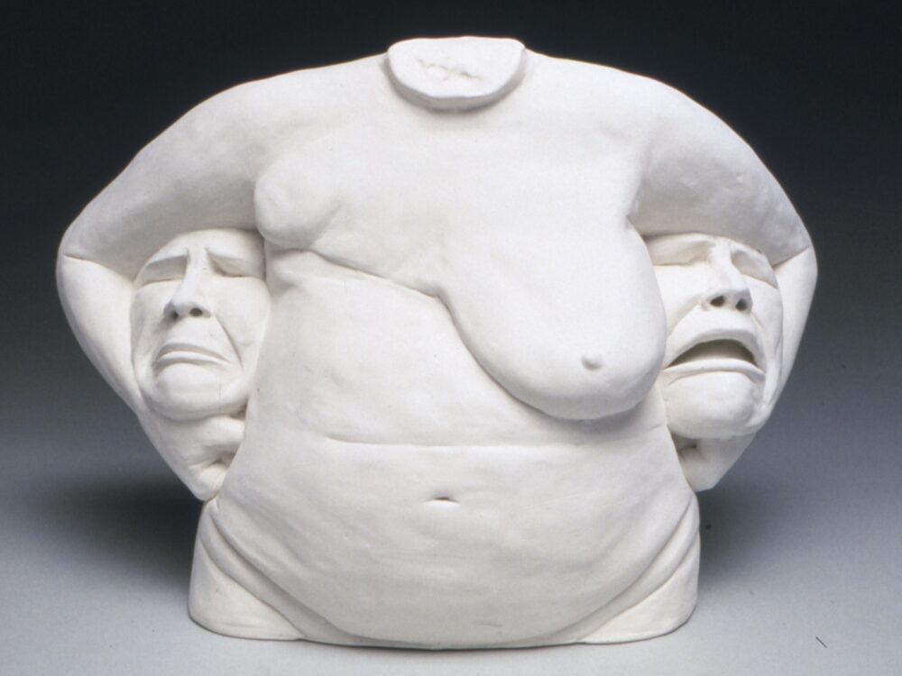 ceramic torso with breasts with a head tucked underneath each arm