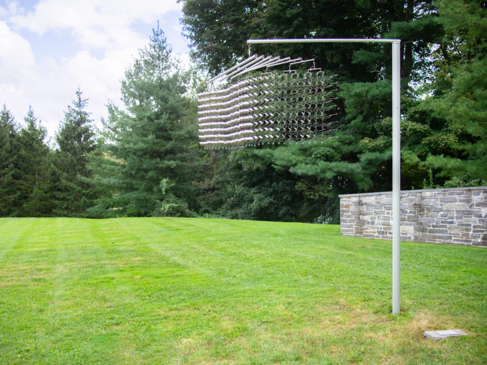 Silvery kinetic sculpture installed on a hanging pole in the Museum's Sculpture Garden.