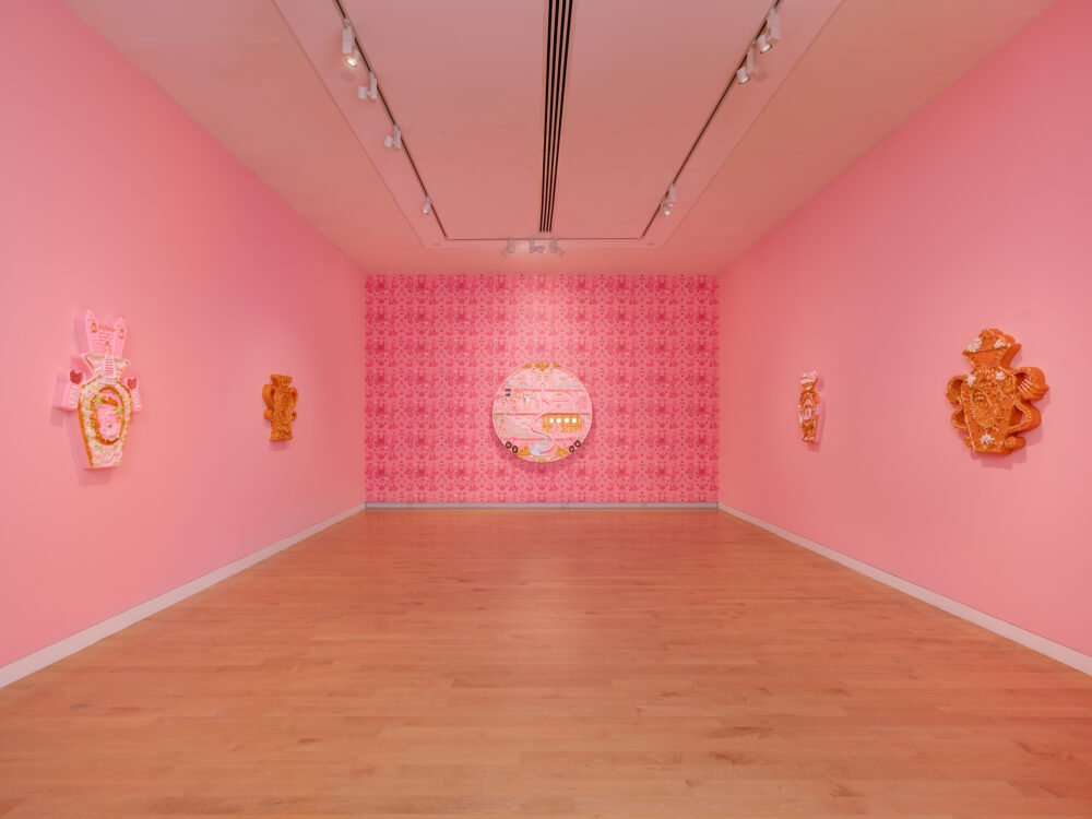 A pink room with pink hued paintings hung on the walls.