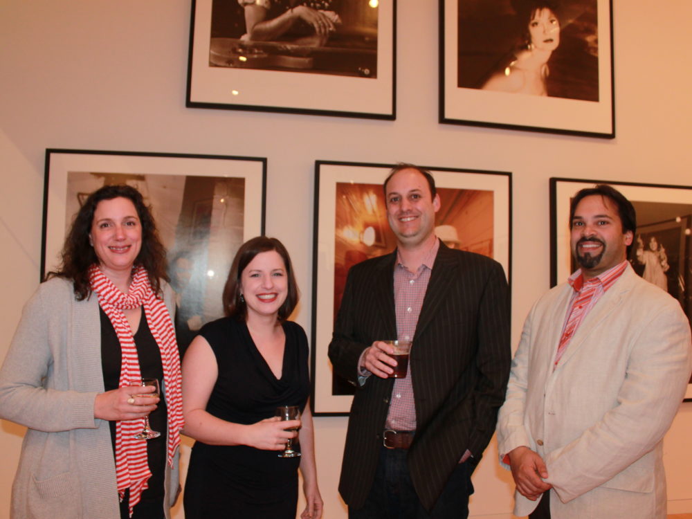 Four people in a gallery with drinks.