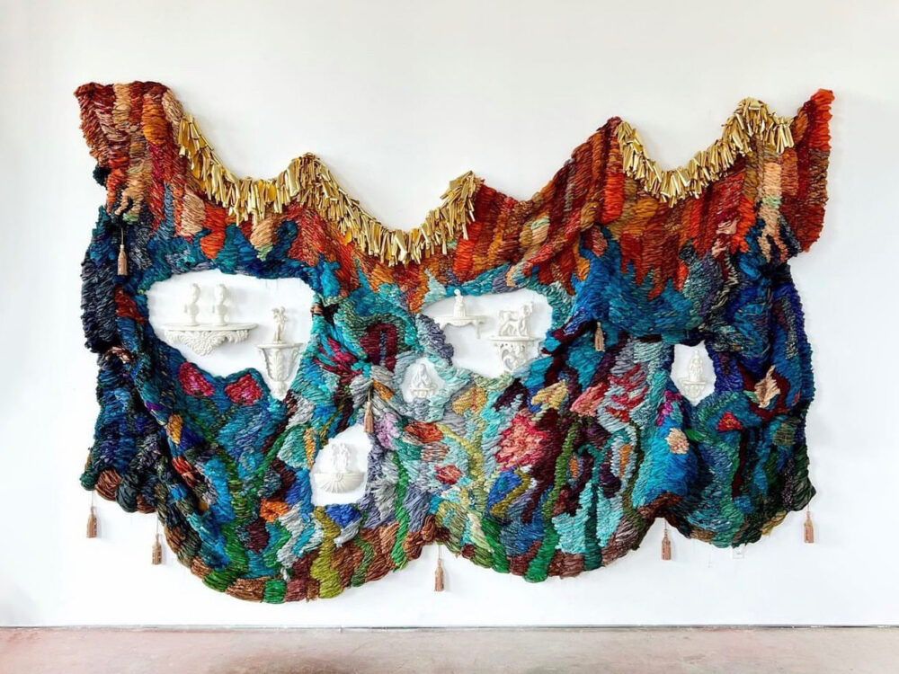 Image of art work made of woven fabric and porcelain objects hanging on a wall